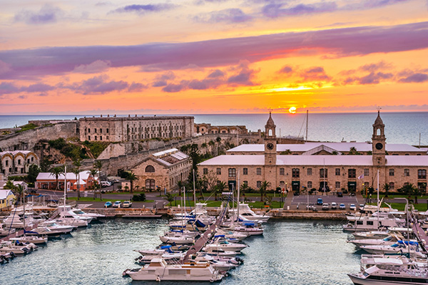Kings Wharf at sunset with luxury boats, the clock towers and Casemates Prison in Bermuda.