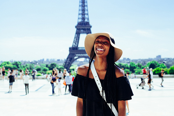 An expat smiling in front of the Eiffel Tower in Paris.