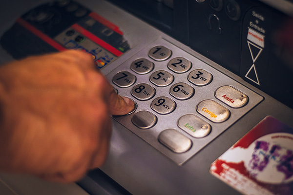 Person, punching their banking numbers into an ATM.