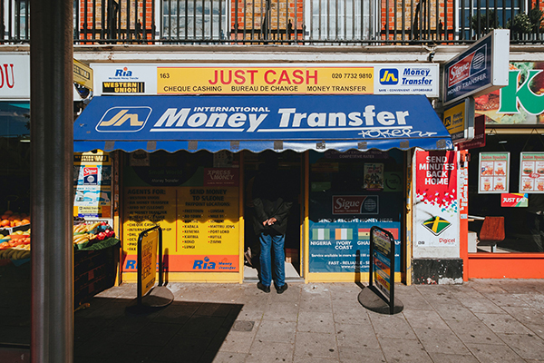 Man entering a money transfer store in a busy city.